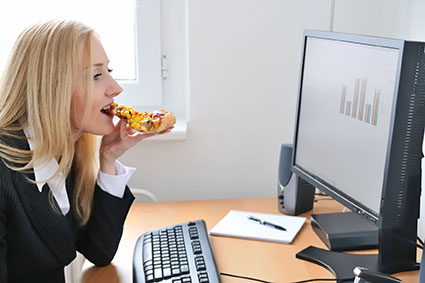 Keine Zeit für gesunde Ernährung: Im täglichen Stress ersetzt oft ein Snack vor dem Computer ein ausgewogenes Mittagessen. Foto: djd/Magnesium-Diasporal/PantherMedia/Martin Novak